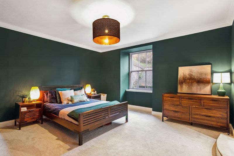 Bedroom styled in deep green with wooden furniture