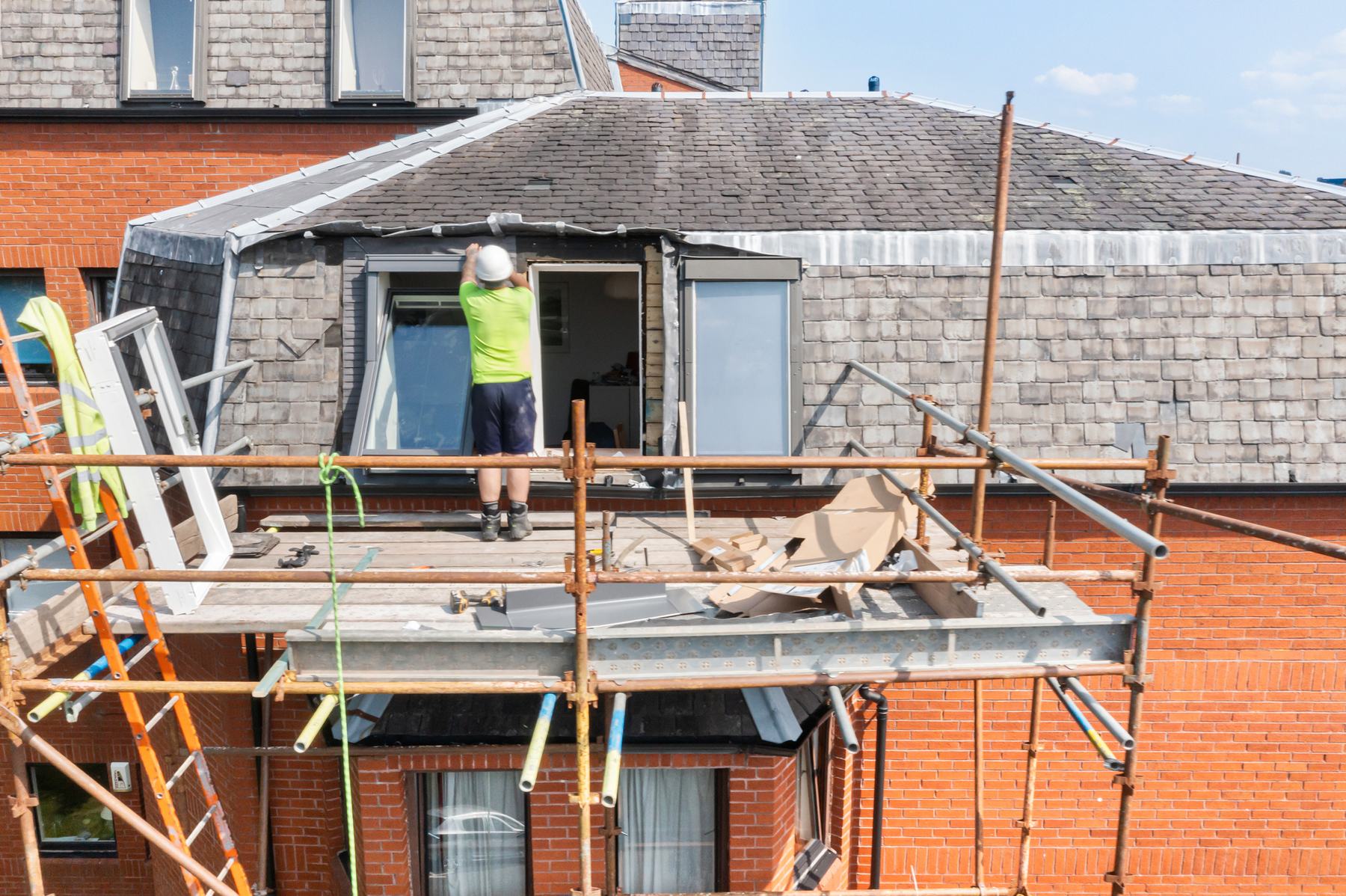 On-site construction photography of a roofer fitting a window