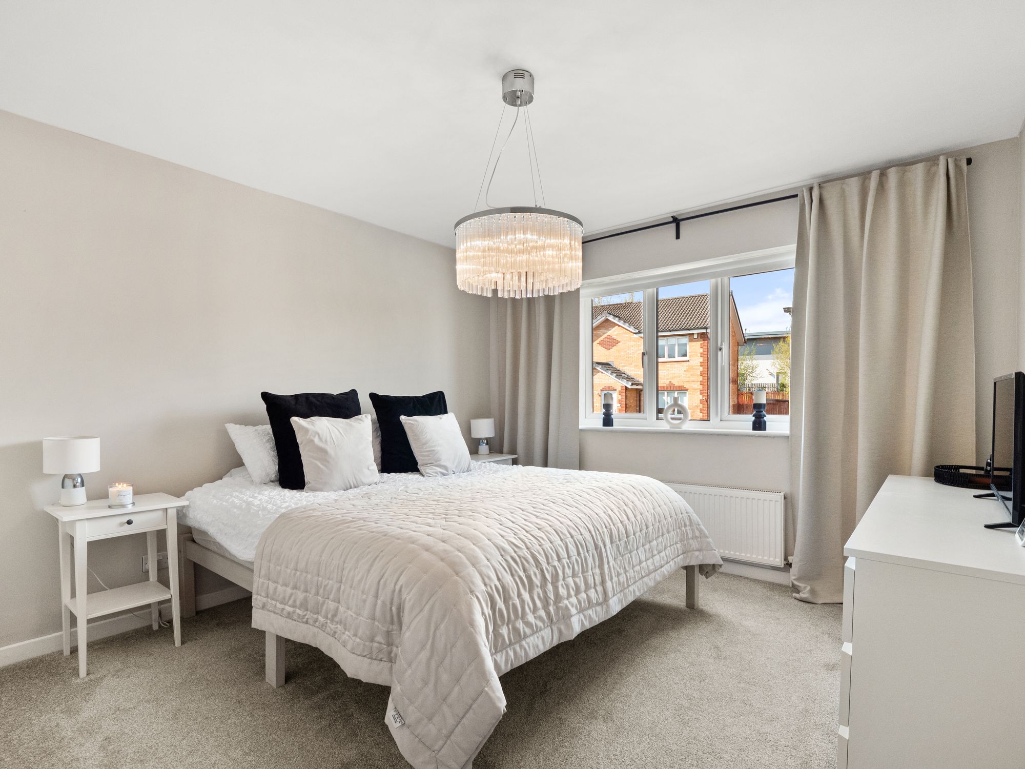 Bedroom in soft beige tones with statement chandelier