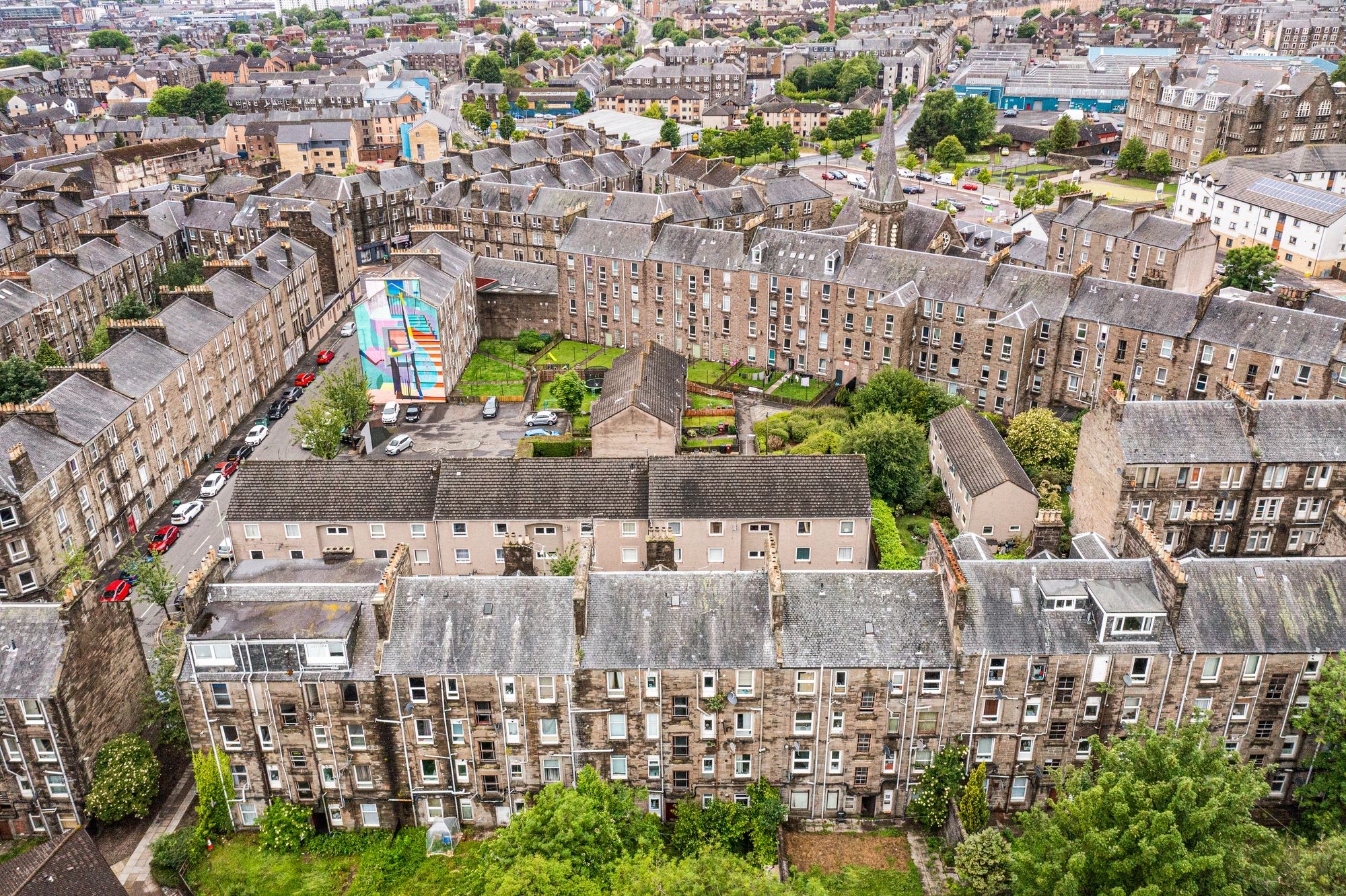 Aerial drone photograph of tenement rooftops and a street mural
