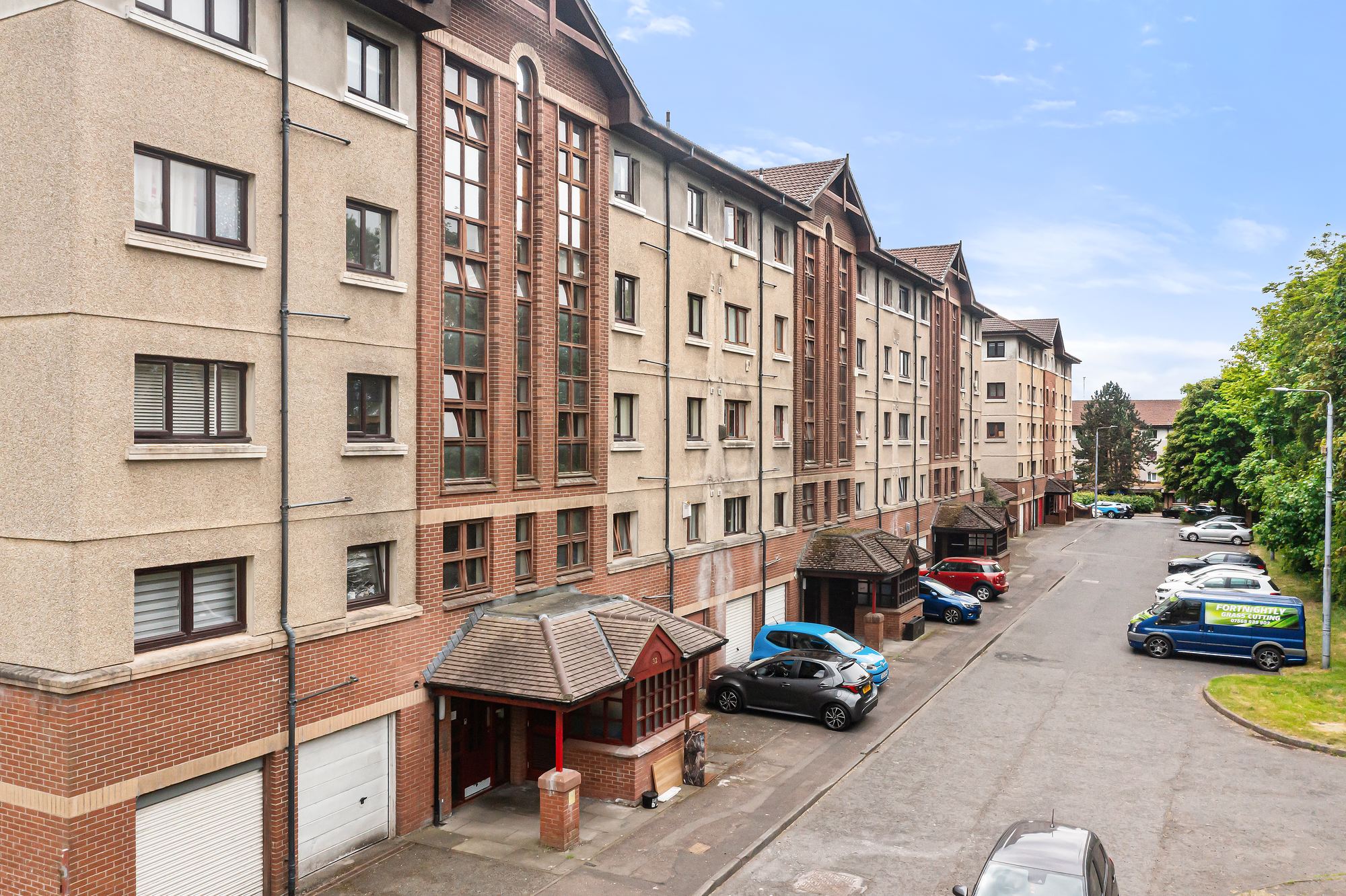 Red brick apartment building street elevation with parked cars