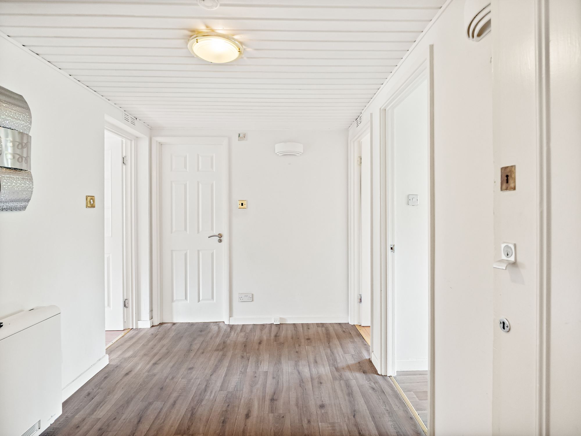 Bright hallway with oak effect flooring and white panelled doors