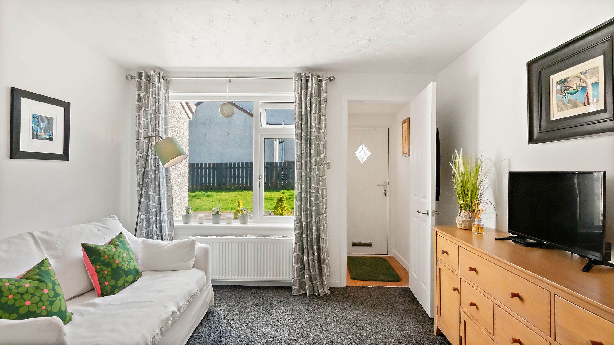 Living room with patterned curtains opening onto hallway