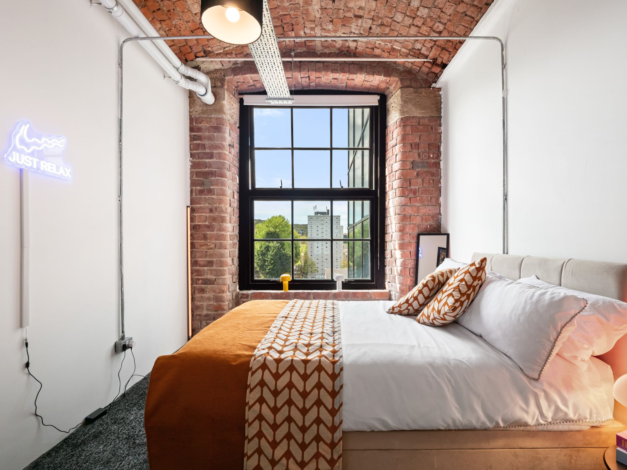 Loft bedroom with exposed brick and neon sign